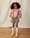 Early Sunday, Joseph Short Dungaree in Moss, made from Cotton Corduroy fabric, featuring short dungaree with adjustable straps, shown in a front view of a model wearing it in a studio setting