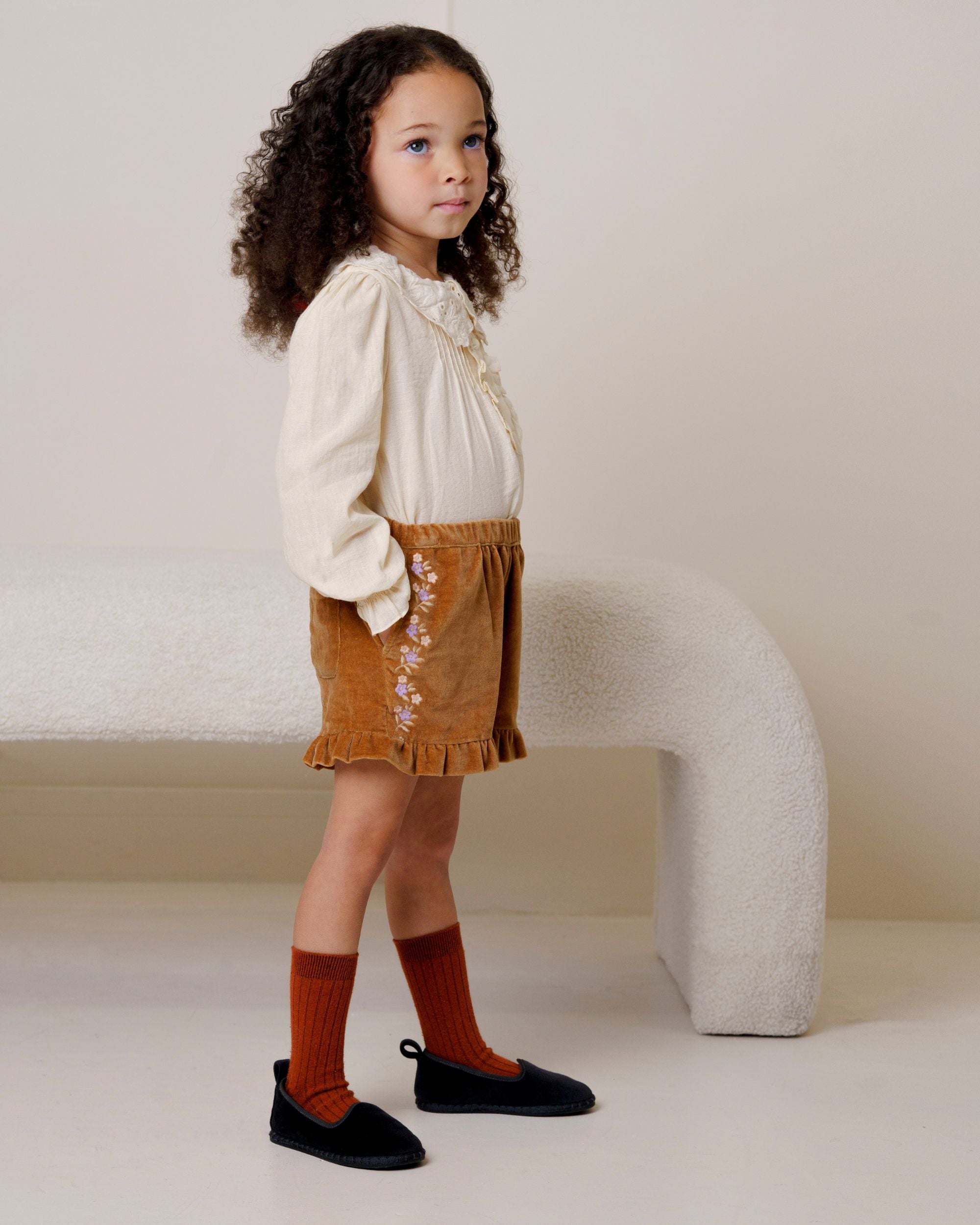 Early Sunday, Joseph Short Dungaree in Almond, made from Dyed Cotton Velvet fabric, featuring Softly structured short dungaree with classic detailing for a vintage-inspired look, shown in a side view of model wearing it