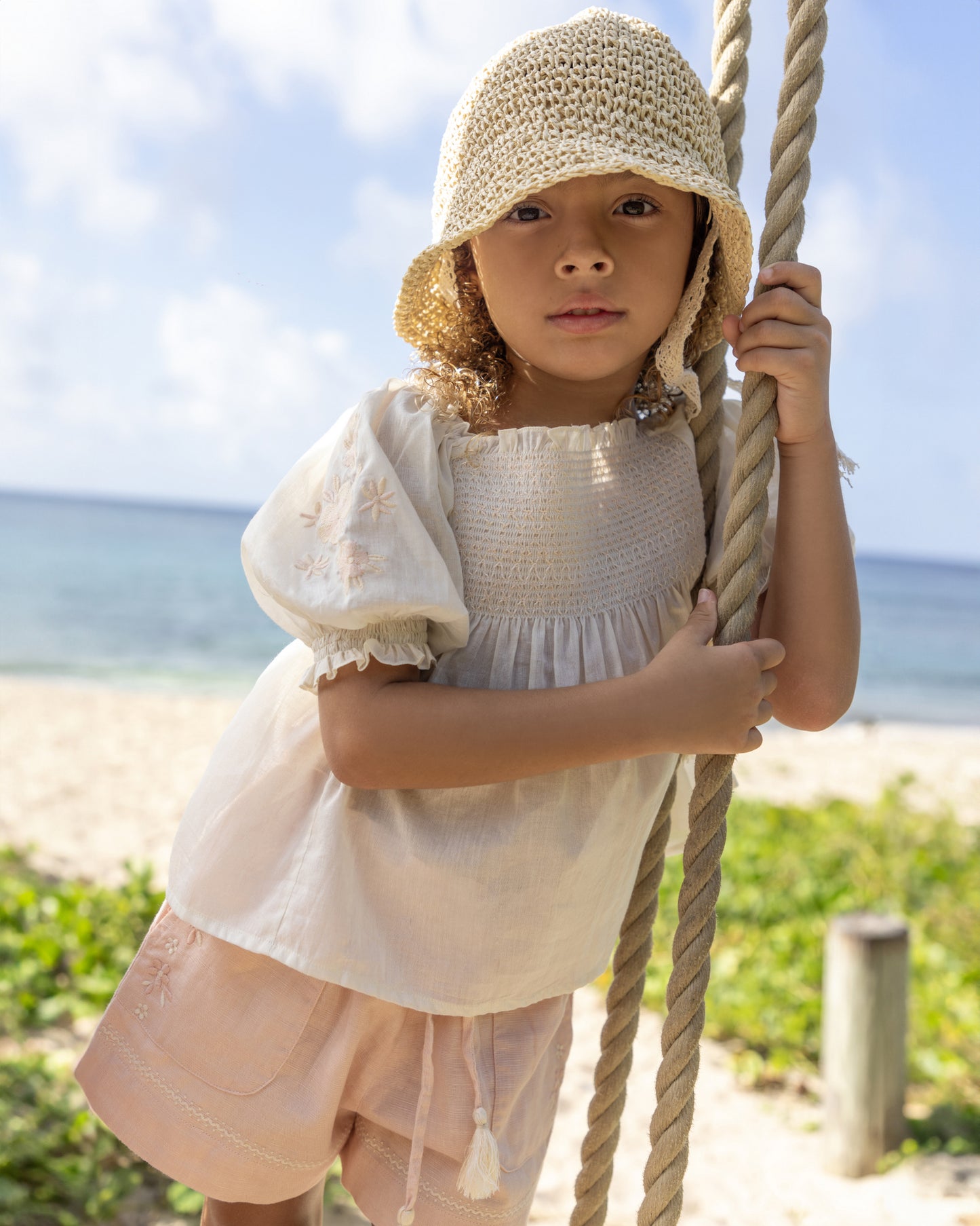 Early Sunday, Judith Blouse in Cream color, made from Cotton Voile fabric, featuring relaxed fit with delicate finishes, combining style and functionality, shown in a front view of model playing outdoors