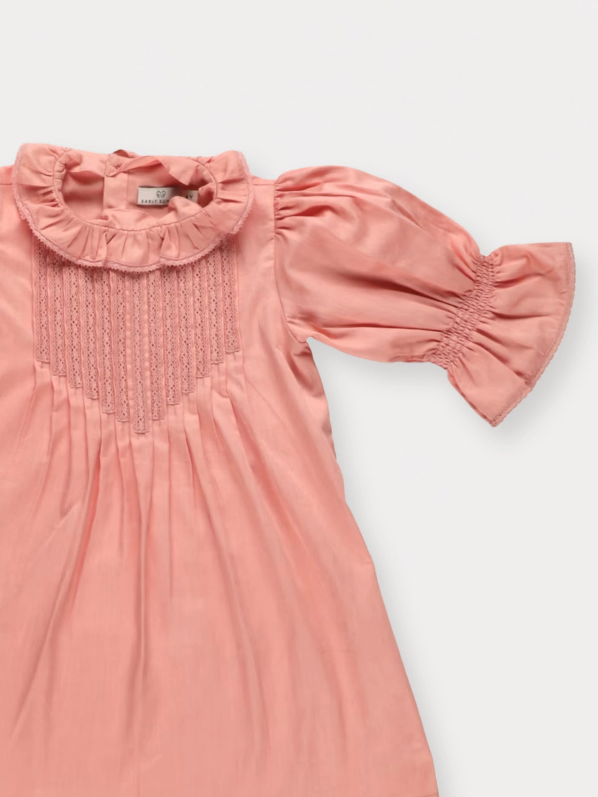 Early Sunday, Julie Dress in Blush Pink, made from Cotton Satin fabric, featuring cute floral embroidery on a Peter Pan collar with a smocked chest, shown in a closeup flat-lay view