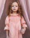 Early Sunday, Julie Dress in Blush Pink, made from Cotton Satin fabric, featuring cute floral embroidery on a Peter Pan collar with a smocked chest, shown in a close up shot of model wearing it