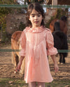 Early Sunday, Julie Dress in Blush Pink, made from Cotton Satin fabric, featuring cute floral embroidery on a Peter Pan collar with a smocked chest, shown in a front view of model wearing it