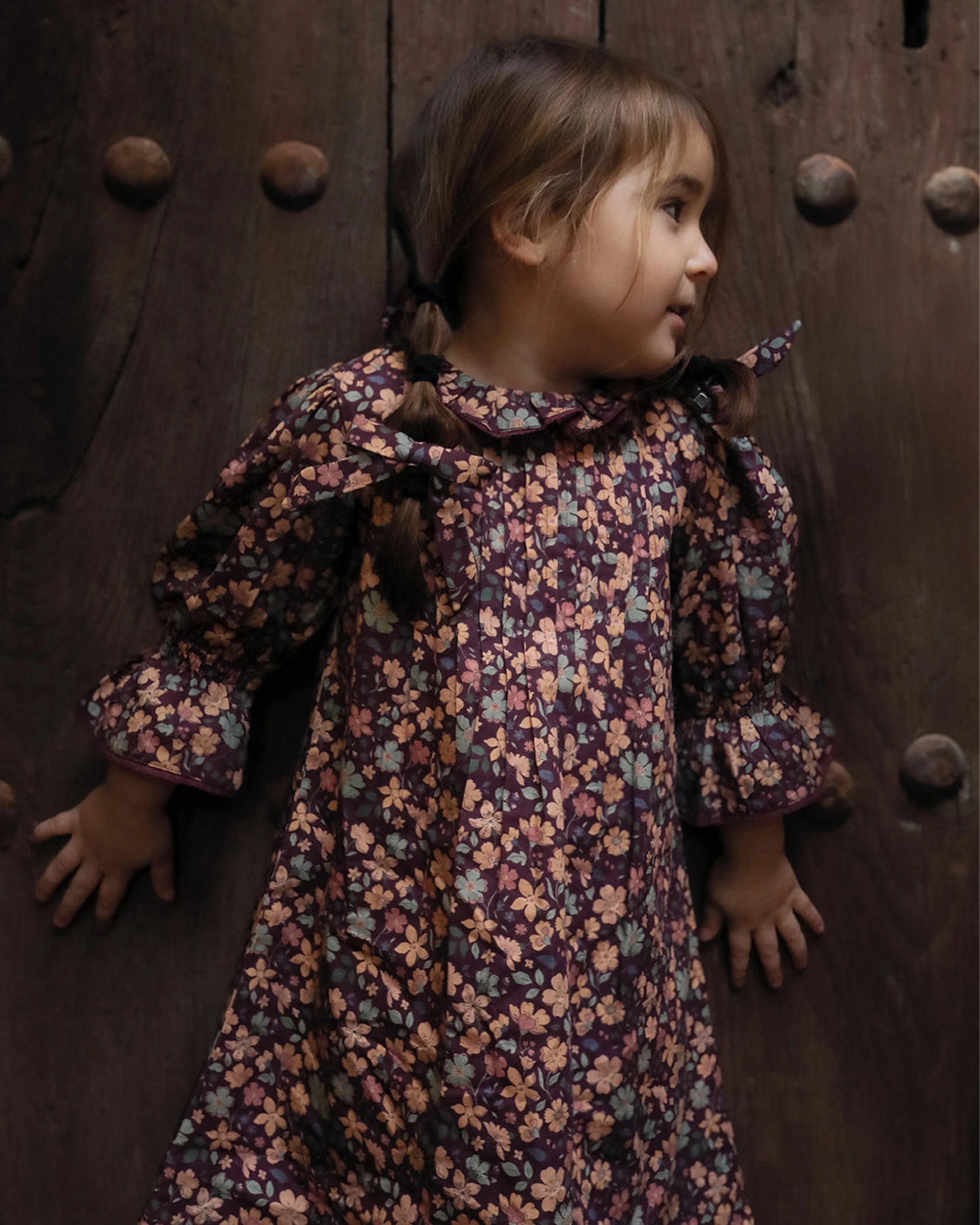Early Sunday, Julie Dress in Plum, made from Printed Cotton Satin fabric, featuring detailed lace gathered sleeves with frilled neckline & floral detailing, shown in a an angled view with a close-up shot
