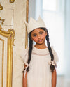Early Sunday, Kids Crown in Hazelnut Cream Nylon Mesh, made from Dyed Nylon Mesh Dobby fabric, featuring a design with pointed tips & an elasticated band, shown in a front view of model wearing it