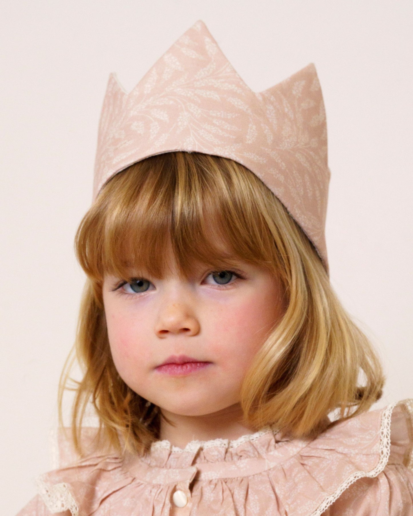 Early Sunday, Kids Crown in Feather print, made from Printed 60s Cotton Cambric fabric, featuring a design with pointed tips & an elasticated band, shown in a close-up shot of a model wearing it