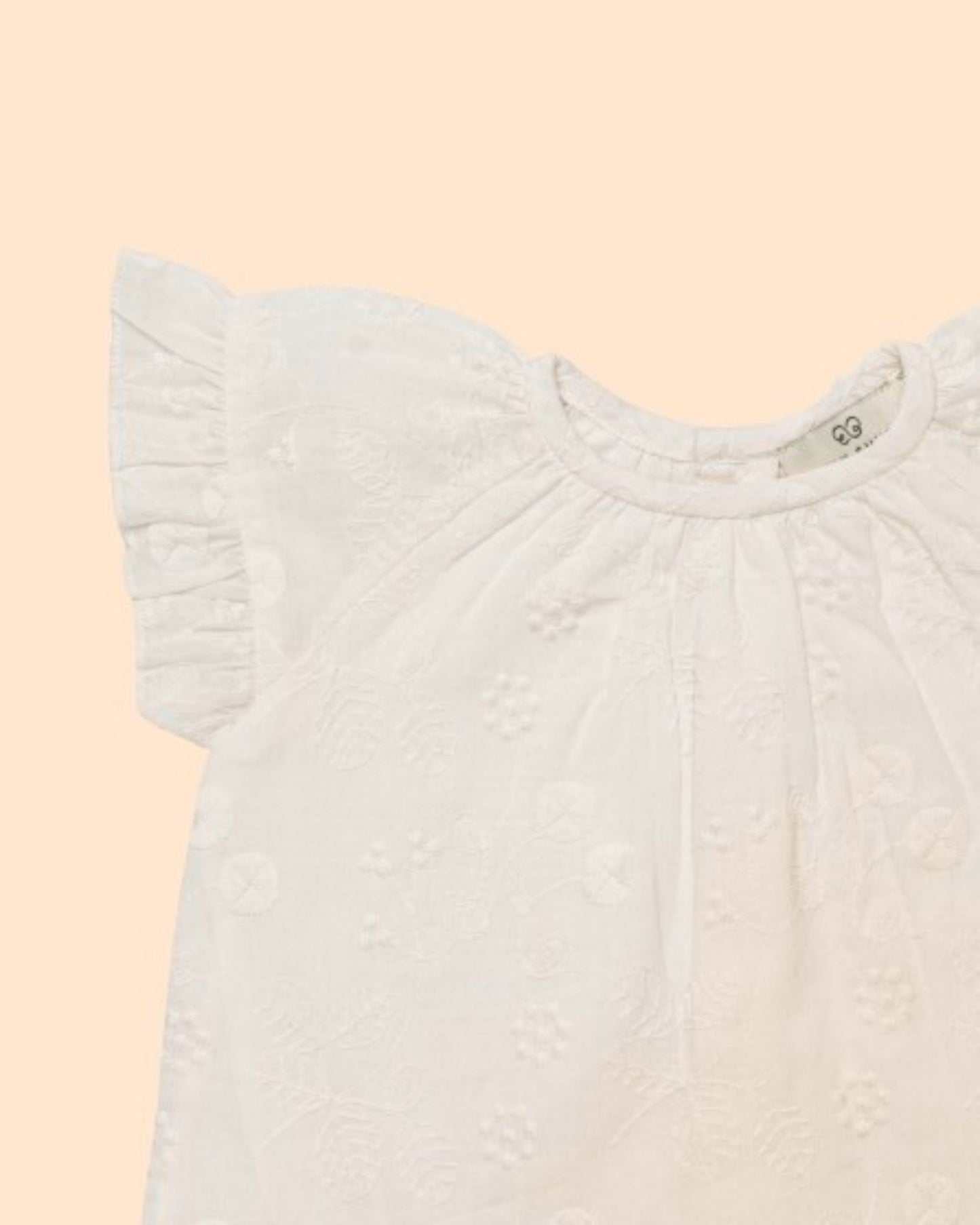 Early Sunday, Kitty Baby Blouse & Bloomer Set in Ivory color, made from 100% Cotton All Over Embroidery fabric, featuring a sleeveless flared sleeves with floral embroidery, shown in a closeup flat-lay view