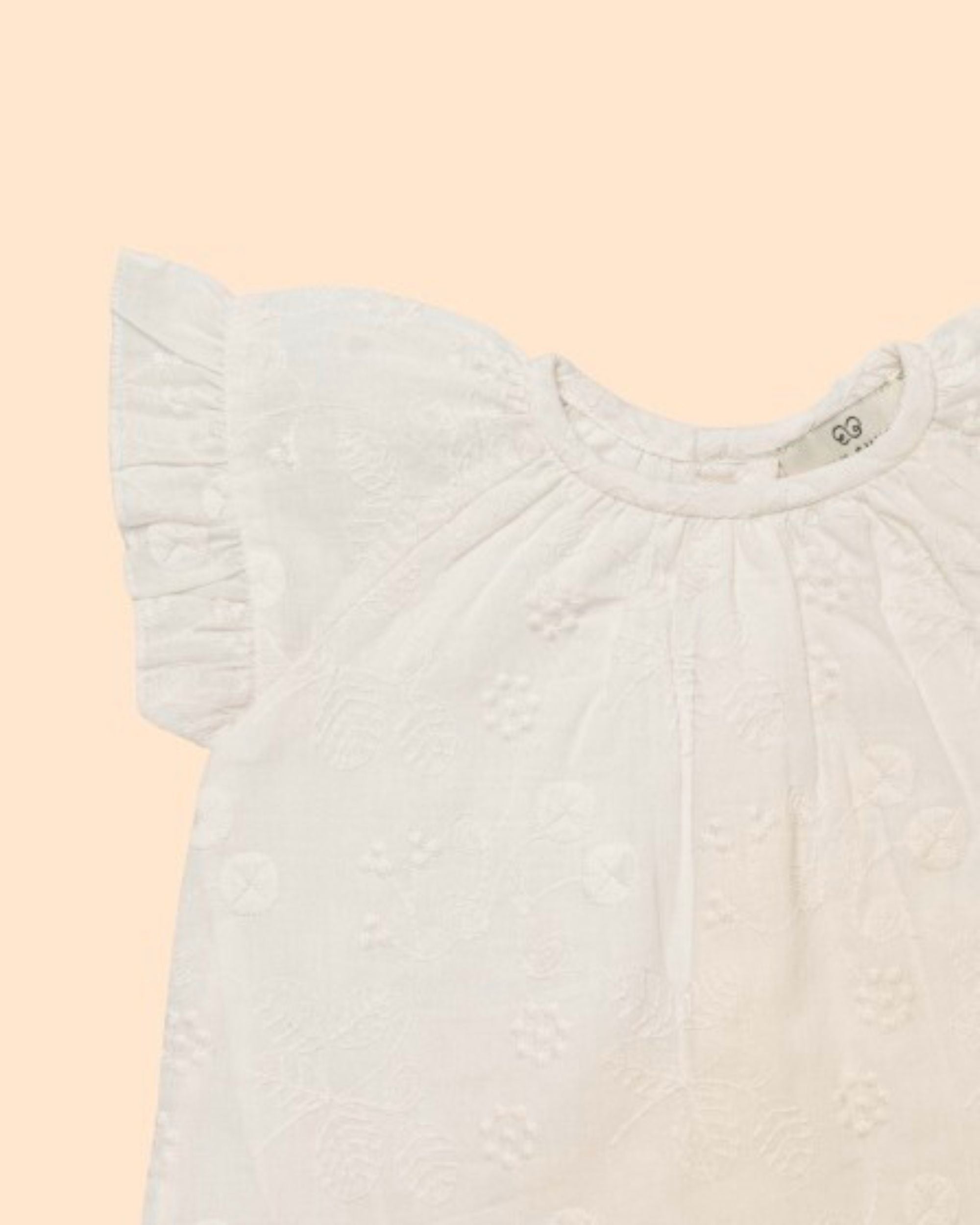 Early Sunday, Kitty Baby Blouse & Bloomer Set in Ivory color, made from 100% Cotton All Over Embroidery fabric, featuring a sleeveless flared sleeves with floral embroidery, shown in a closeup flat-lay view