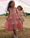 Early Sunday, Laura Dress in Candy Floss color, made from 100% cotton double gauze solid fabric, featuring Crisscross ruffle straps with delicate trim accents and a softly gathered tiered skirt, shown in a Model walking / movement shot