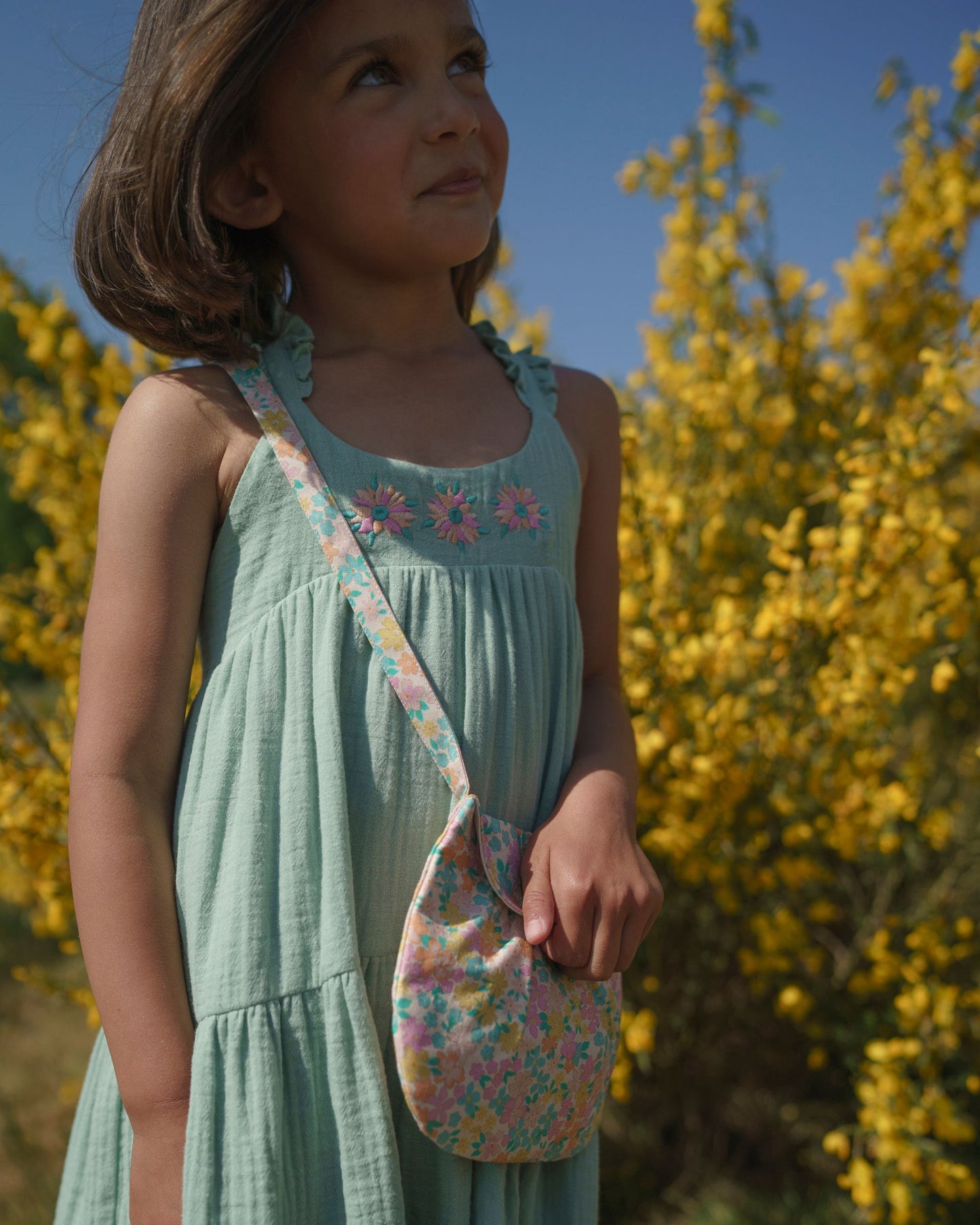 Early Sunday, Laura Dress in Mint color, made from 100% cotton double gauze solid fabric, featuring Crisscross ruffle straps with delicate trim accents and a softly gathered tiered skirt, shown in a close up shot of model wearing it