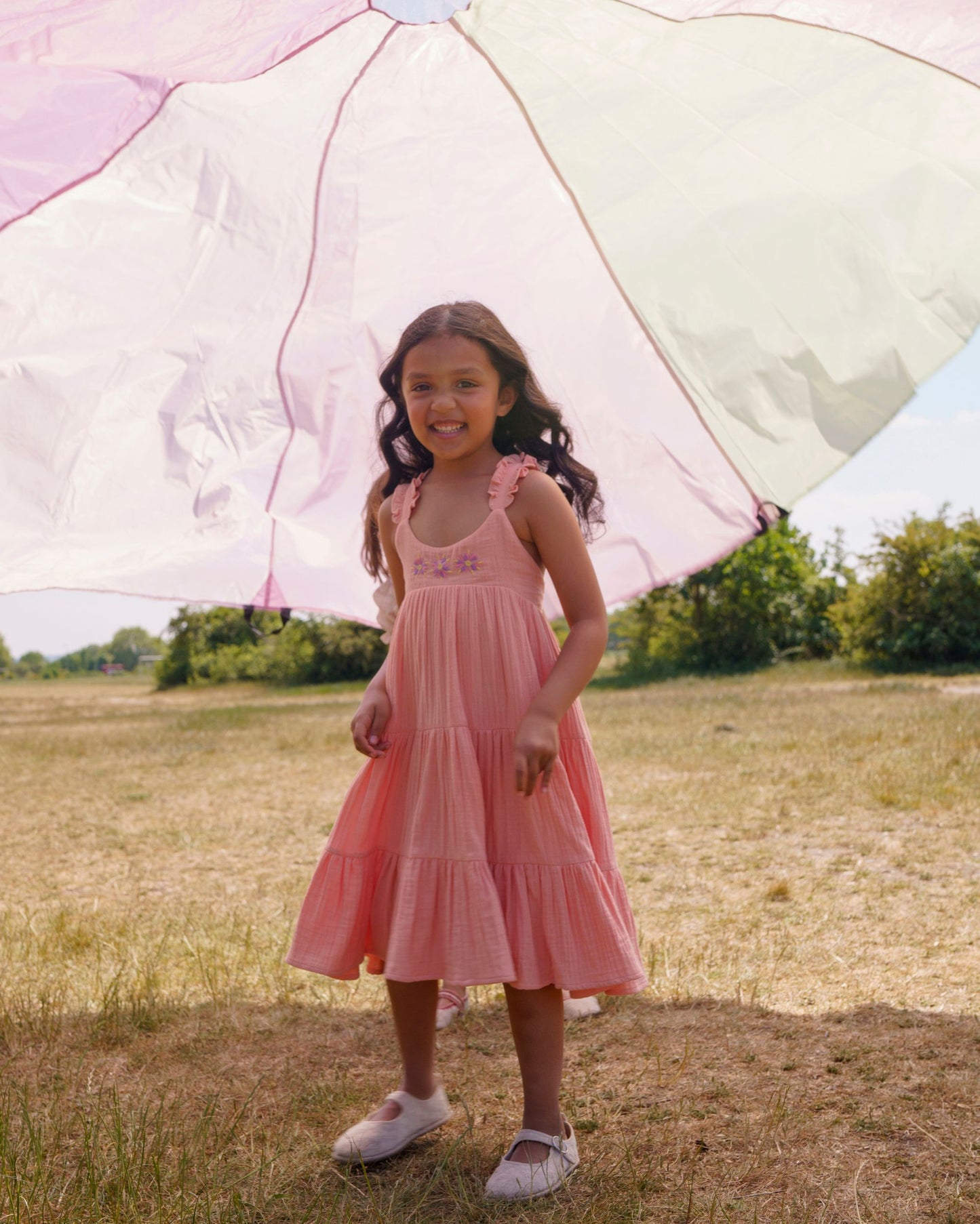 Early Sunday, Laura Dress in Candy Floss color, made from 100% cotton double gauze solid fabric, featuring Crisscross ruffle straps with delicate trim accents and a softly gathered tiered skirt, shown in a front view of model wearing