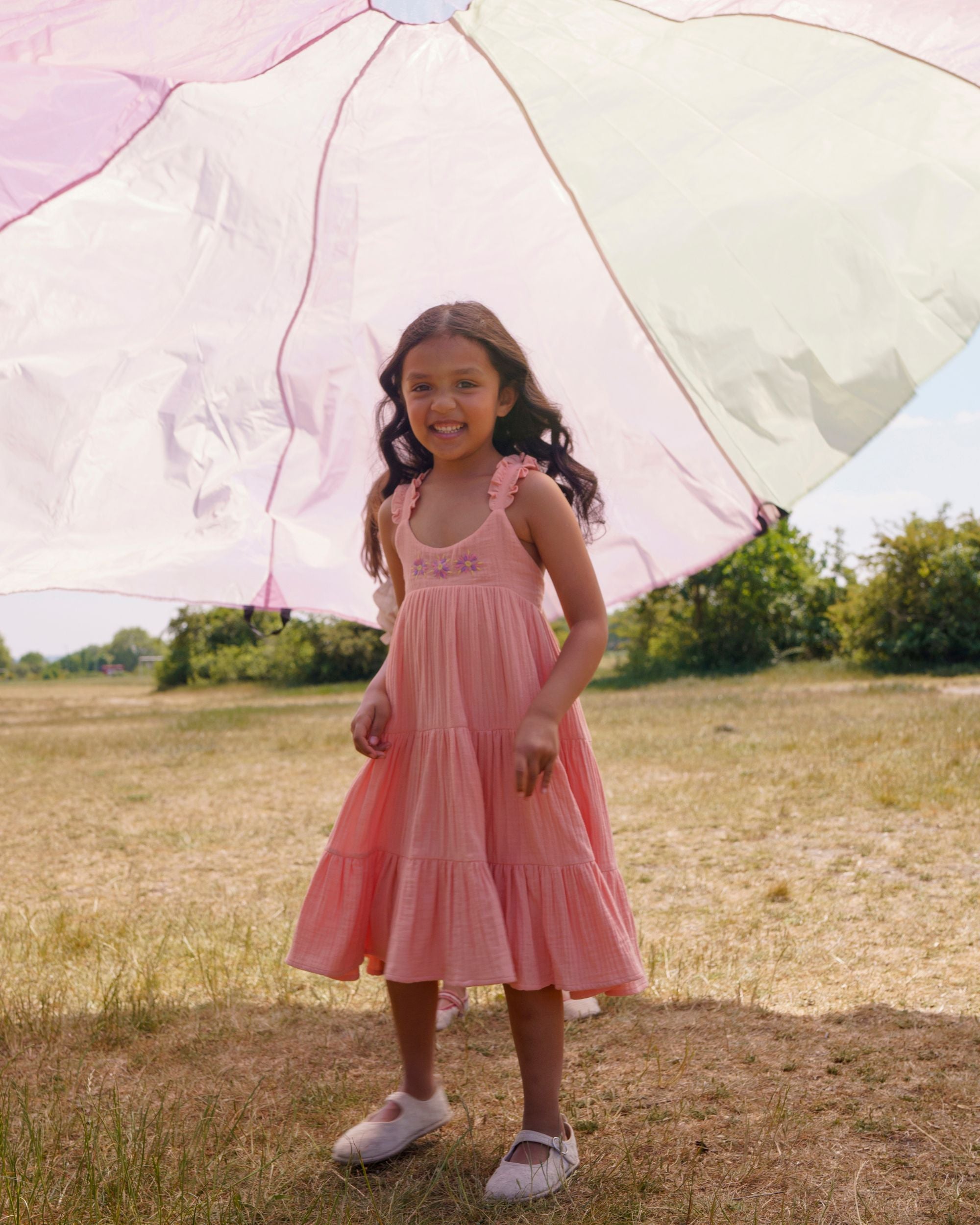 Early Sunday, Laura Dress in Candy Floss color, made from 100% cotton double gauze solid fabric, featuring Crisscross ruffle straps with delicate trim accents and a softly gathered tiered skirt, shown in a front view of model wearing