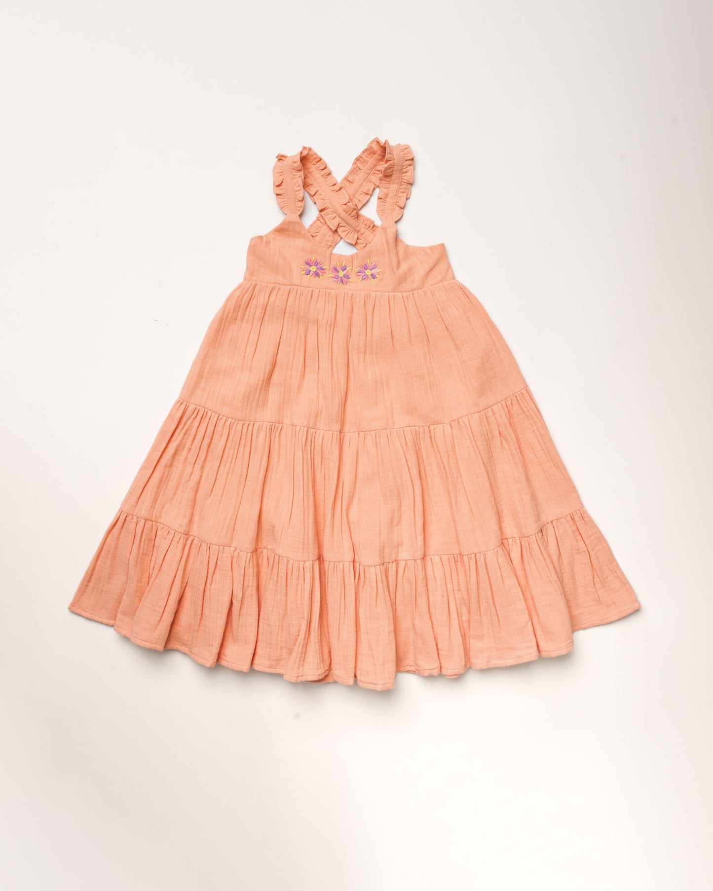 Early Sunday, Laura Dress in Candy Floss color, made from 100% cotton double gauze solid fabric, featuring Crisscross ruffle straps with delicate trim accents and a softly gathered tiered skirt, shown in a front flat-lay view