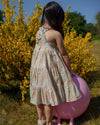 Early Sunday, Laura Dress in Emma Floral Mint color, made from printed 60s cotton cambric fabric, featuring Crisscross ruffle straps with delicate trim accents and a softly gathered tiered skirt, shown in a model wearing outdoors