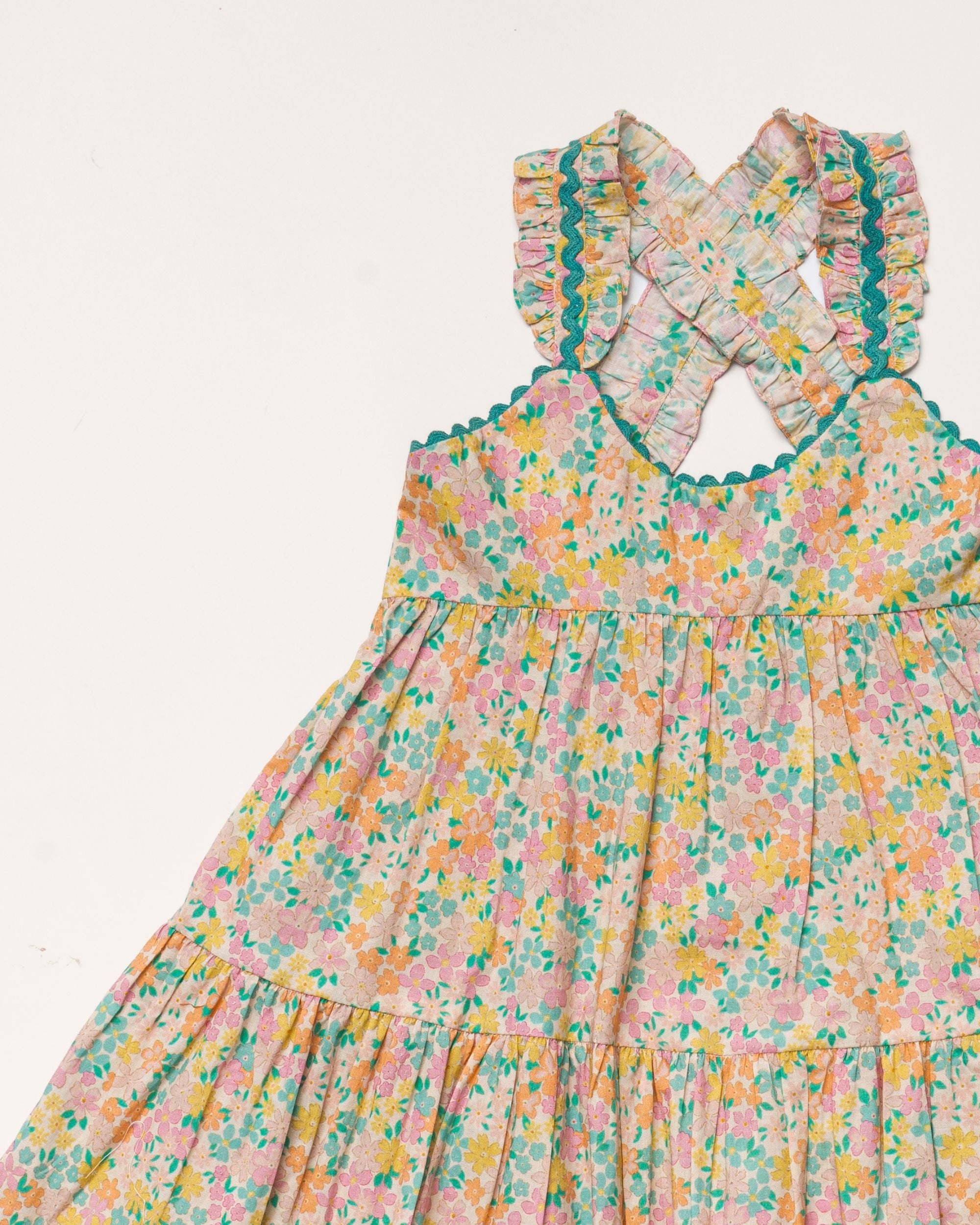 Early Sunday, Laura Dress in Emma Floral Mint color, made from printed 60s cotton cambric fabric, featuring Crisscross ruffle straps with delicate trim accents and a softly gathered tiered skirt, shown in a closeup flat-lay view
