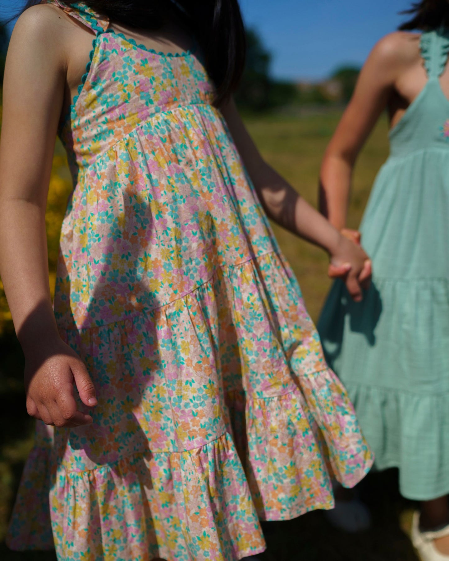 Early Sunday, Laura Dress in Emma Floral Mint color, made from printed 60s cotton cambric fabric, featuring Crisscross ruffle straps with delicate trim accents and a softly gathered tiered skirt, shown in a side view of model wearing it