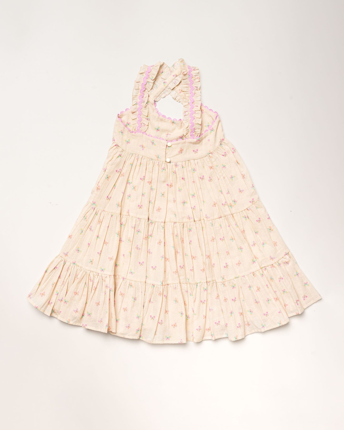 Early Sunday, Laura Dress in Butterfly Print color, made from printed cotton tiny swiss dobby fabric, featuring Crisscross ruffle straps with delicate trim accents and a softly gathered tiered skirt, shown in a back flat-lay view