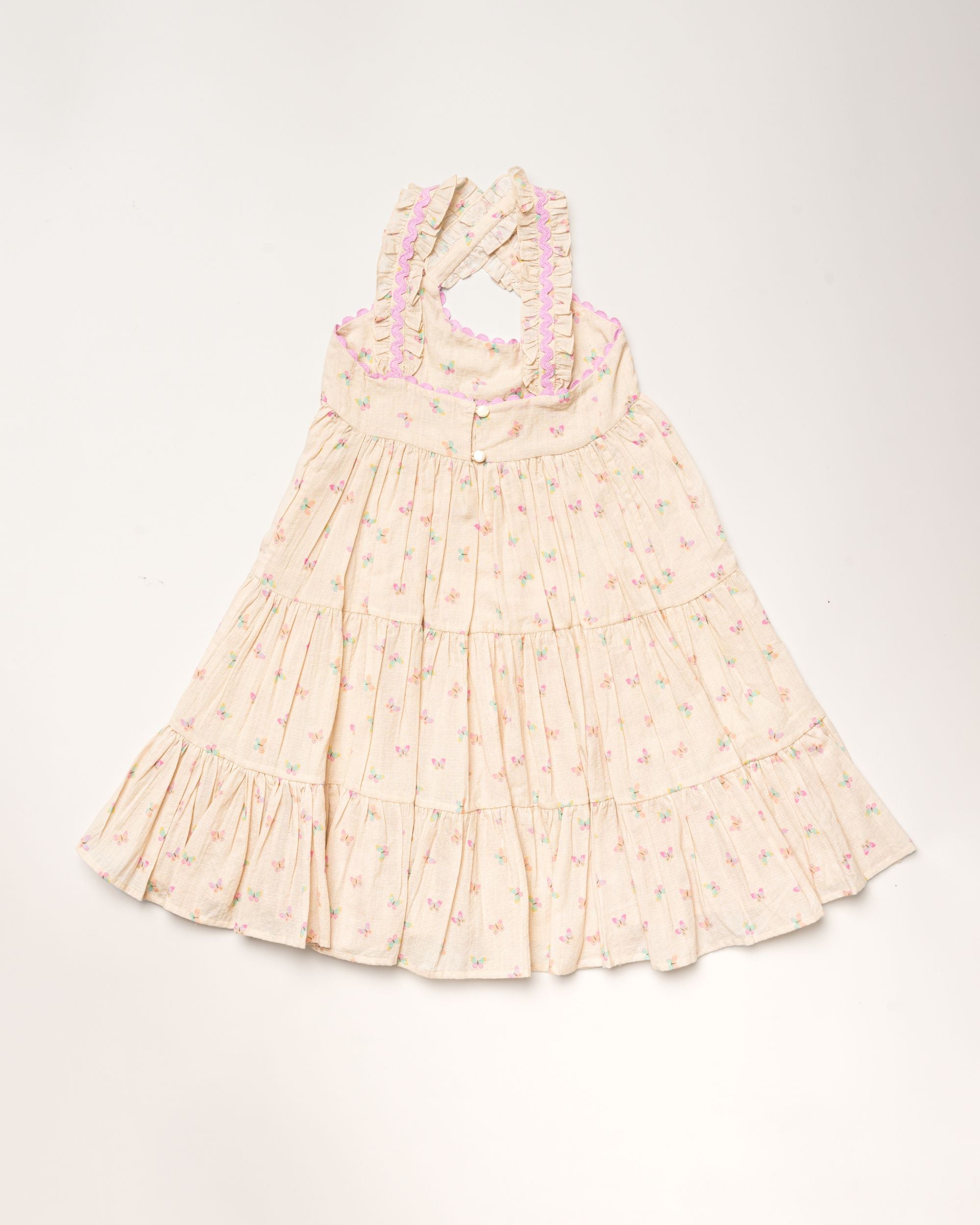 Early Sunday, Laura Dress in Butterfly Print color, made from printed cotton tiny swiss dobby fabric, featuring Crisscross ruffle straps with delicate trim accents and a softly gathered tiered skirt, shown in a back flat-lay view