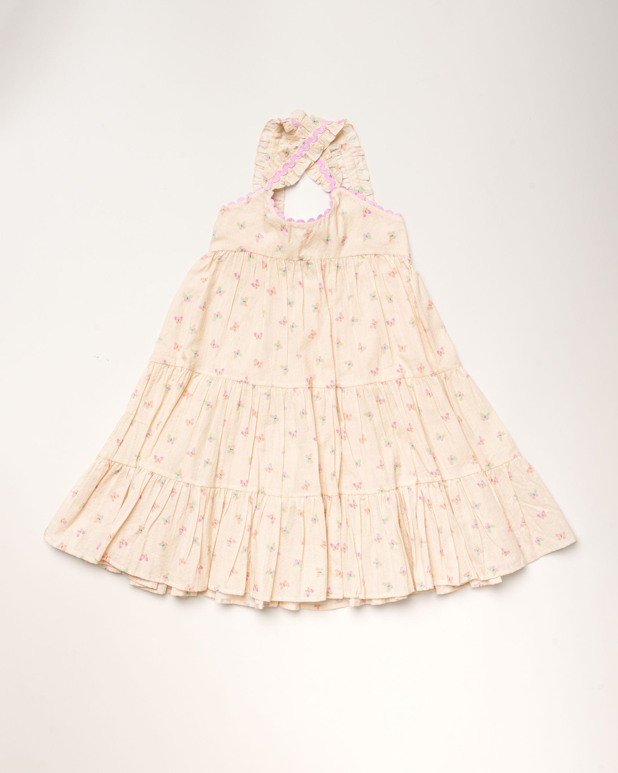 Early Sunday, Laura Dress in Butterfly Print color, made from printed cotton tiny swiss dobby fabric, featuring Crisscross ruffle straps with delicate trim accents and a softly gathered tiered skirt, shown in a front flat-lay view