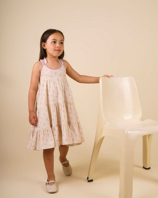 Early Sunday, Laura Dress in Butterfly Print color, made from printed cotton tiny swiss dobby fabric, featuring Crisscross ruffle straps with delicate trim accents and a softly gathered tiered skirt, shown in a model standing facing front wearing