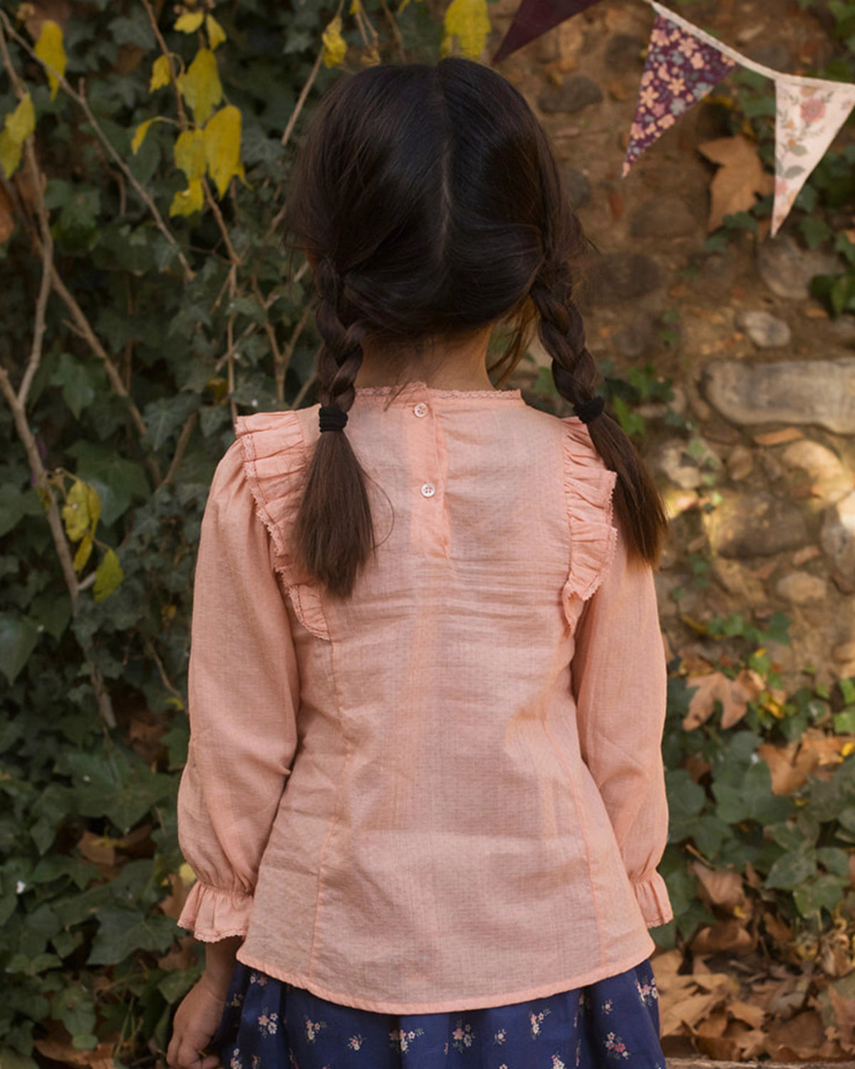 Early Sunday, Lauren Blouse in Blush, made from Cotton Jeera Dobby Voile fabric, featuring layered lace-trimmed ruffles and delicate pintuck detailing on the yoke, shown in a back view of model wearing outdoors
