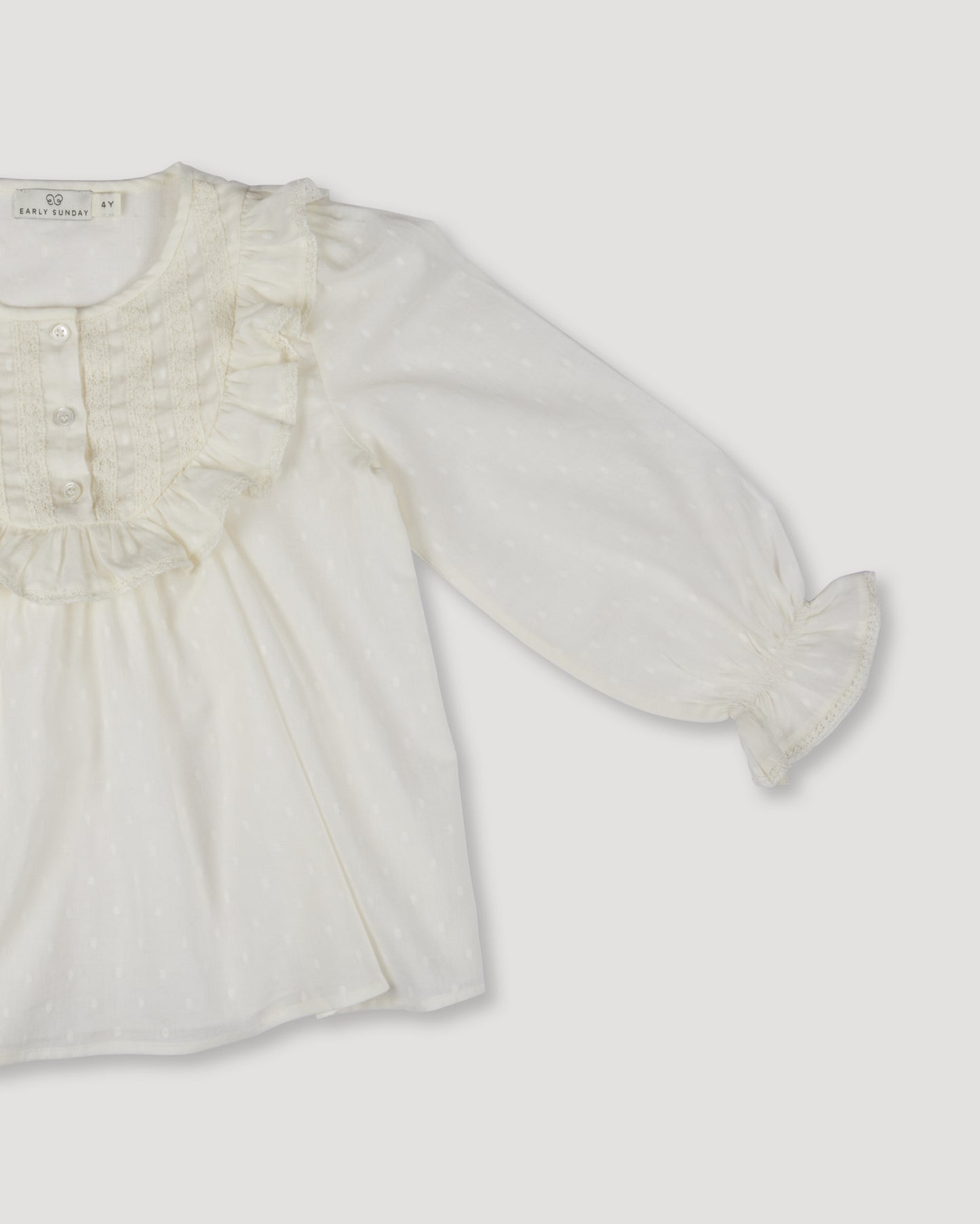 Early Sunday, Lauren Blouse in Ecru, made from Cotton Swiss Dobby fabric, featuring relaxed fit with a floral embroidered yoke, shown in a closeup flat-lay view