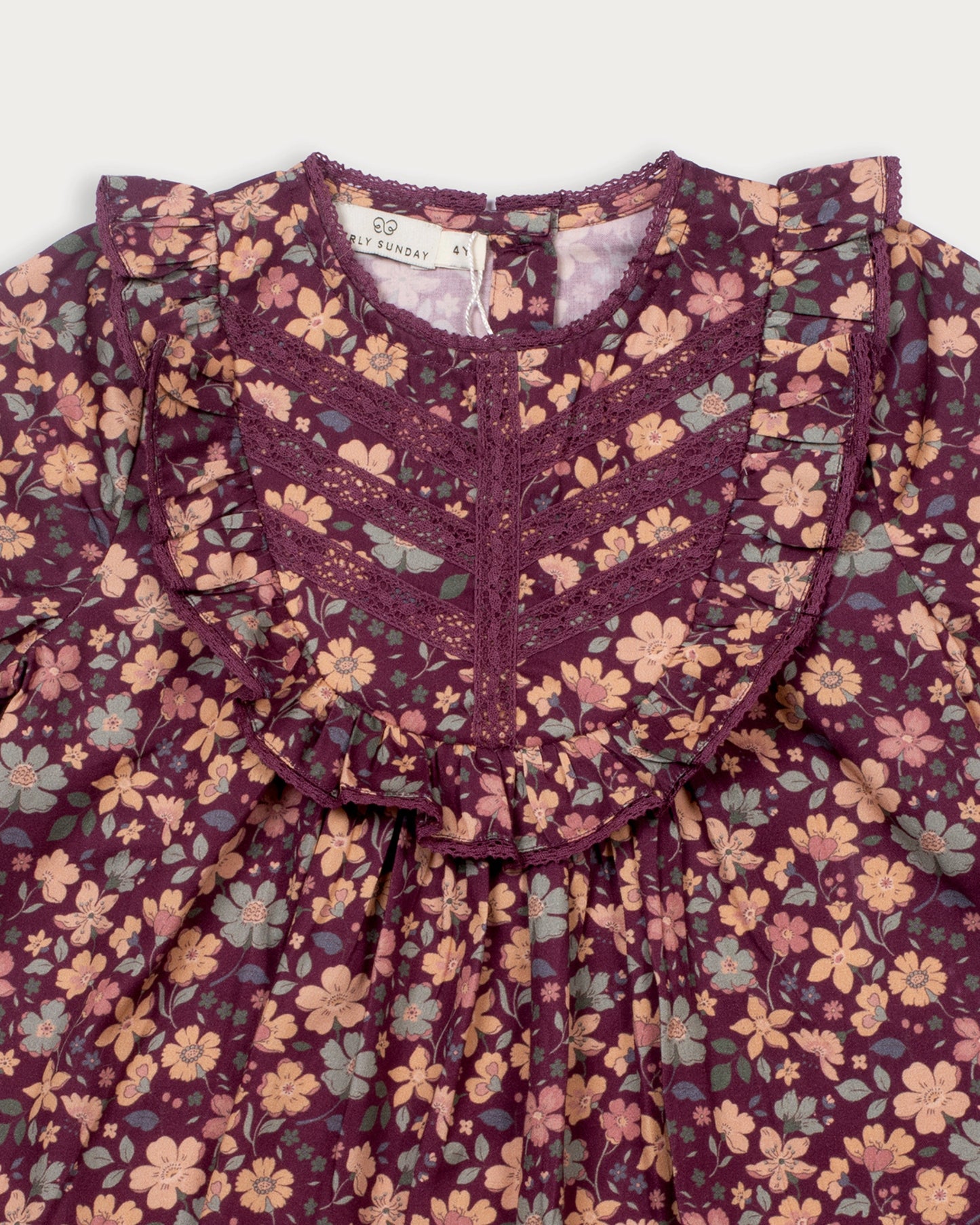 Early Sunday, Lauren Blouse in Plum, made from Printed Cotton Satin fabric, featuring layered lace-trimmed ruffles and delicate pintuck detailing on the yoke, shown in a closeup flat-lay view