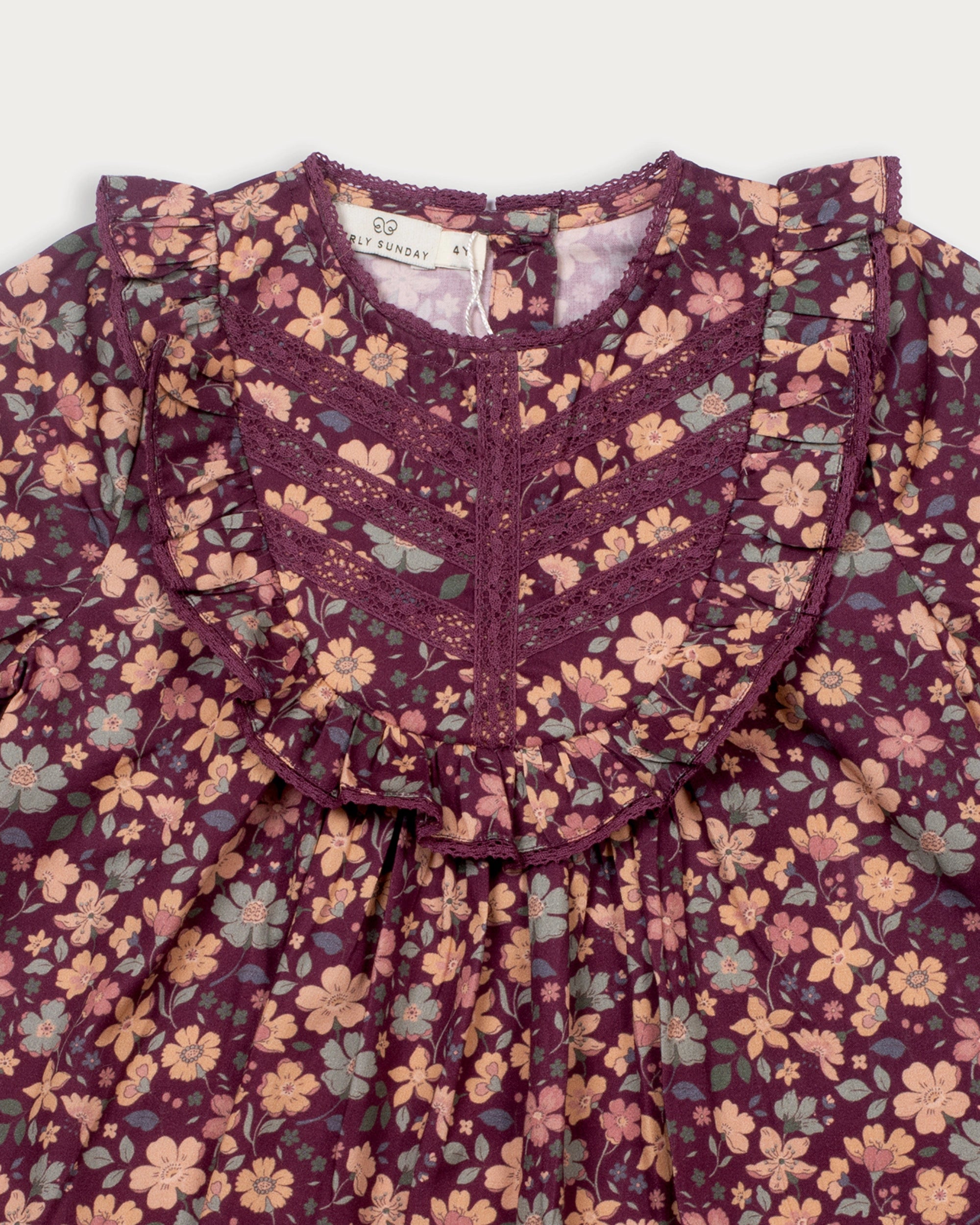 Early Sunday, Lauren Blouse in Plum, made from Printed Cotton Satin fabric, featuring layered lace-trimmed ruffles and delicate pintuck detailing on the yoke, shown in a closeup flat-lay view
