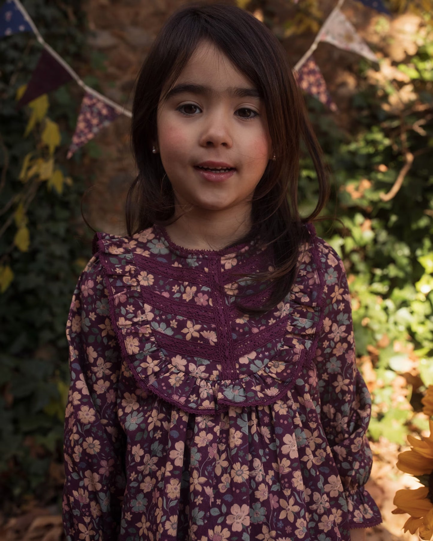 Early Sunday, Lauren Blouse in Plum, made from Printed Cotton Satin fabric, featuring layered lace-trimmed ruffles and delicate pintuck detailing on the yoke, shown in a close up shot of model wearing it