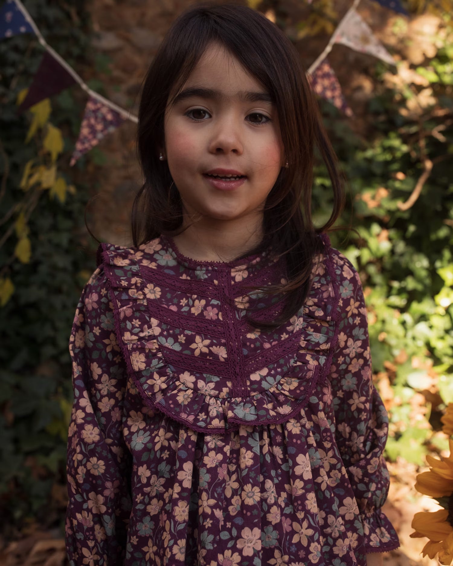 Early Sunday, Lauren Blouse in Plum, made from Printed Cotton Satin fabric, featuring layered lace-trimmed ruffles and delicate pintuck detailing on the yoke, shown in a close up shot of model wearing it