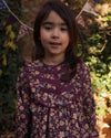 Early Sunday, Lauren Blouse in Plum, made from Printed Cotton Satin fabric, featuring layered lace-trimmed ruffles and delicate pintuck detailing on the yoke, shown in a close up shot of model wearing it