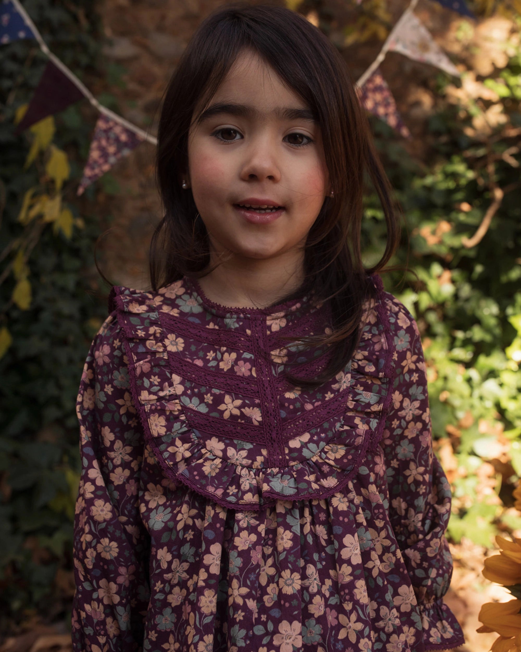 Early Sunday, Lauren Blouse in Plum, made from Printed Cotton Satin fabric, featuring layered lace-trimmed ruffles and delicate pintuck detailing on the yoke, shown in a close up shot of model wearing it