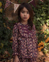 Early Sunday, Lauren Blouse in Plum, made from Printed Cotton Satin fabric, featuring layered lace-trimmed ruffles and delicate pintuck detailing on the yoke, shown in a front view of model wearing it