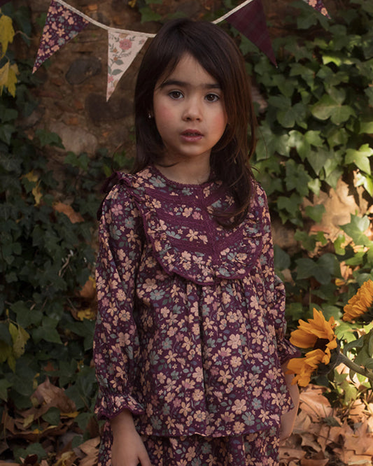Early Sunday, Lauren Blouse in Plum, made from Printed Cotton Satin fabric, featuring layered lace-trimmed ruffles and delicate pintuck detailing on the yoke, shown in a front view of model wearing it