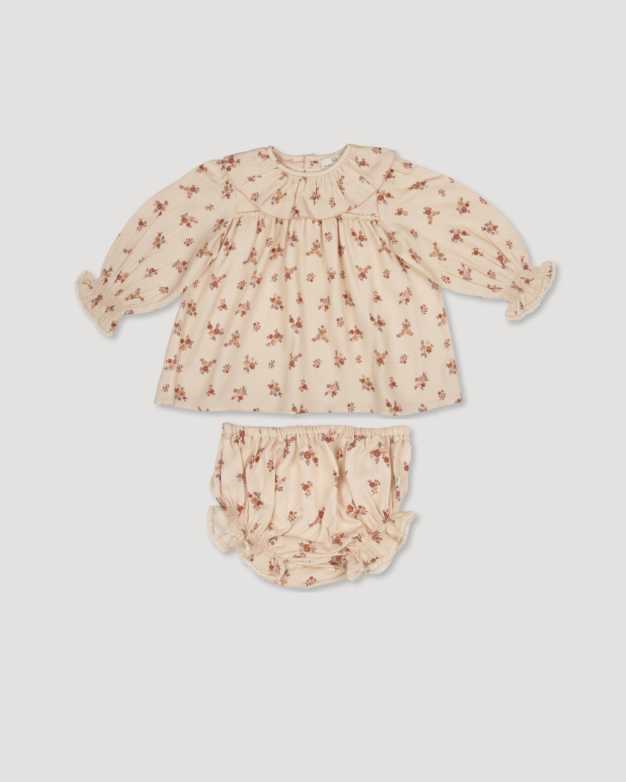 Early Sunday, Libby Baby Dress & Bloomer Set in Ditsy Bouquet Cream print color, made from Printed Viscose Rayon Twill fabric, featuring long sleeves with frilly neck & floral print, shown in a front flat-lay view