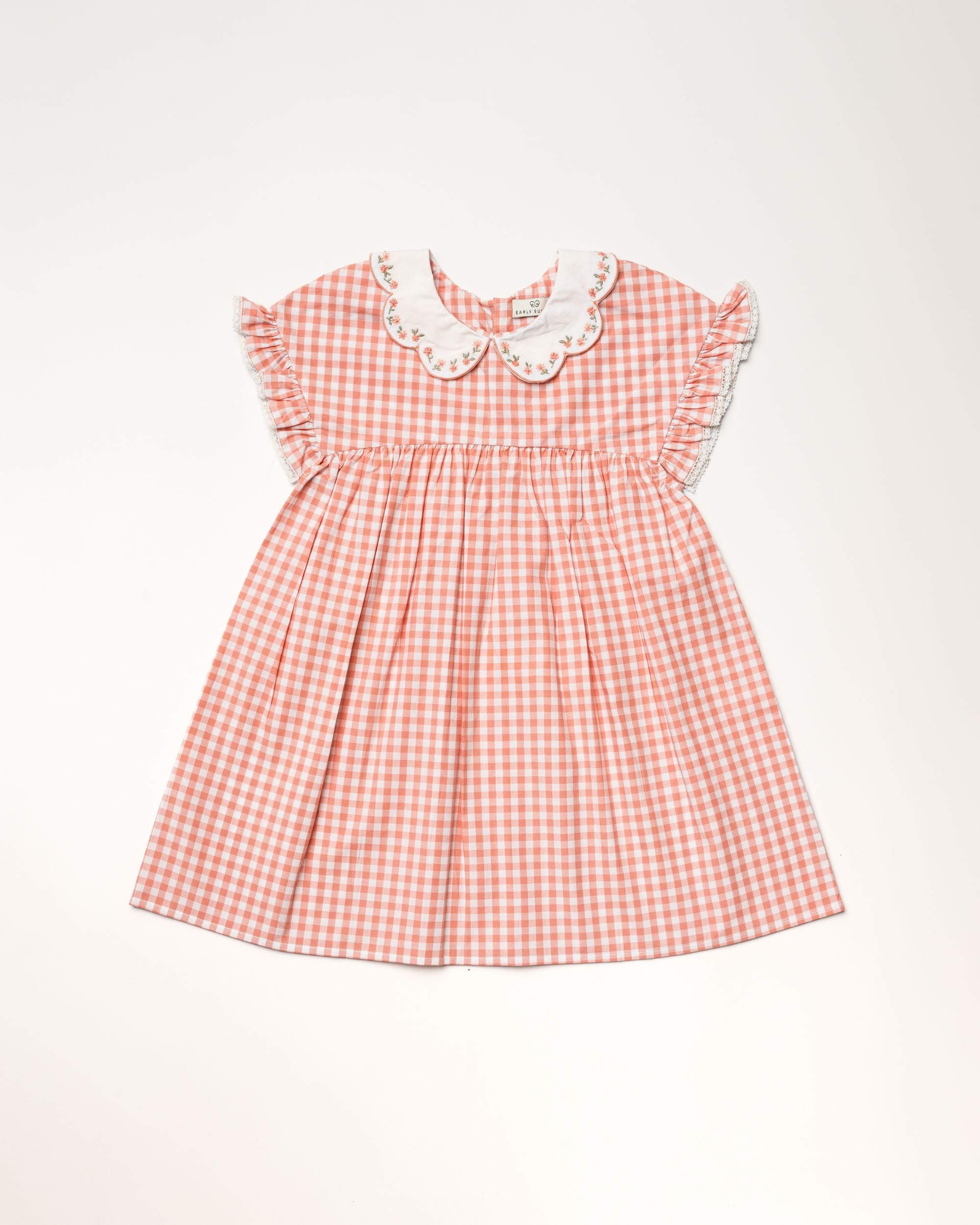 Early Sunday, Lila Dress in Peony color, made from 100% cotton gingham checks fabric, featuring Scalloped neckline with contrast stitching, flutter sleeves, gentle gathers, and embroidered hem detail, shown in a front flat-lay view