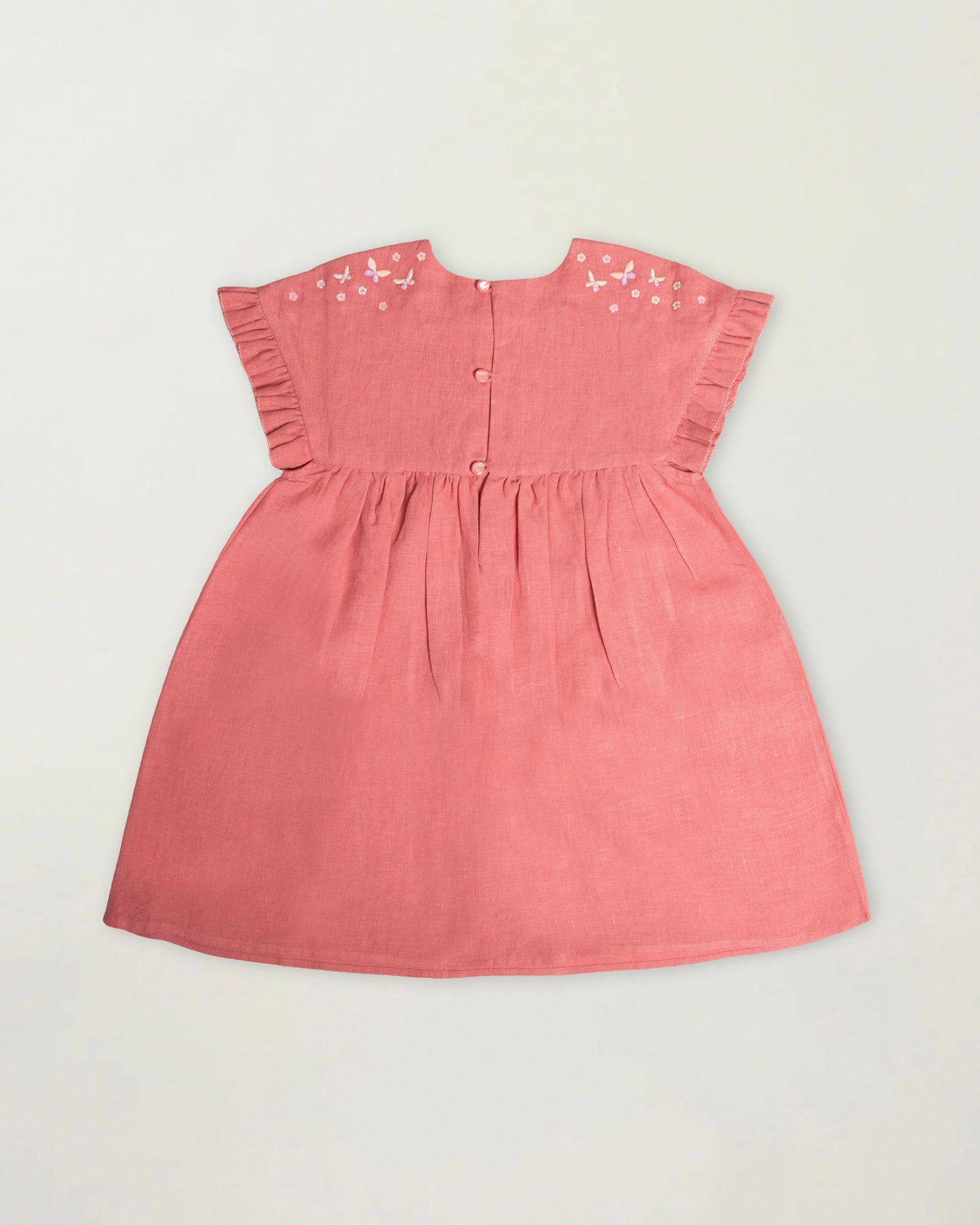 Early Sunday, Lila Dress in Peony color, made from 70% cotton 30% linen solid fabric, featuring Scalloped neckline with contrast stitching, flutter sleeves, gentle gathers, and embroidered hem detail, shown in a back flat-lay view