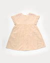 Early Sunday, Lila Dress in Sand color, made from 70% cotton 30% linen solid fabric, featuring Scalloped neckline with contrast stitching, flutter sleeves, gentle gathers, and embroidered hem detail, shown in a back flat-lay view