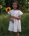 Early Sunday, Lila Dress in Painted Bouquet color, made from printed 70% cotton 30% linen fabric, featuring Scalloped neckline with contrast stitching, flutter sleeves, gentle gathers, and embroidered hem detail, shown in a front view of model wearing