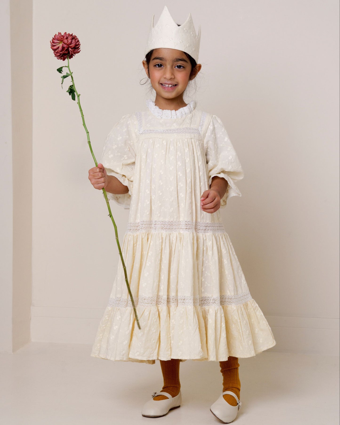 Early Sunday, Lilly Dress in Hazelnut Cream, made from All-Over Embroidered Cotton Cambric fabric, featuring Delicate floral embroidery placed softly across the dress for a timeless, heirloom-inspired finish, shown in a front view of a model wearing it in a studio setting
