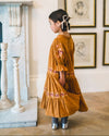 Early Sunday, Lilly Dress in Almond, made from Dyed Cotton Double Gauze fabric, featuring Delicate floral embroidery placed softly across the dress for a timeless, heirloom-inspired finish, shown in a side view of model wearing it