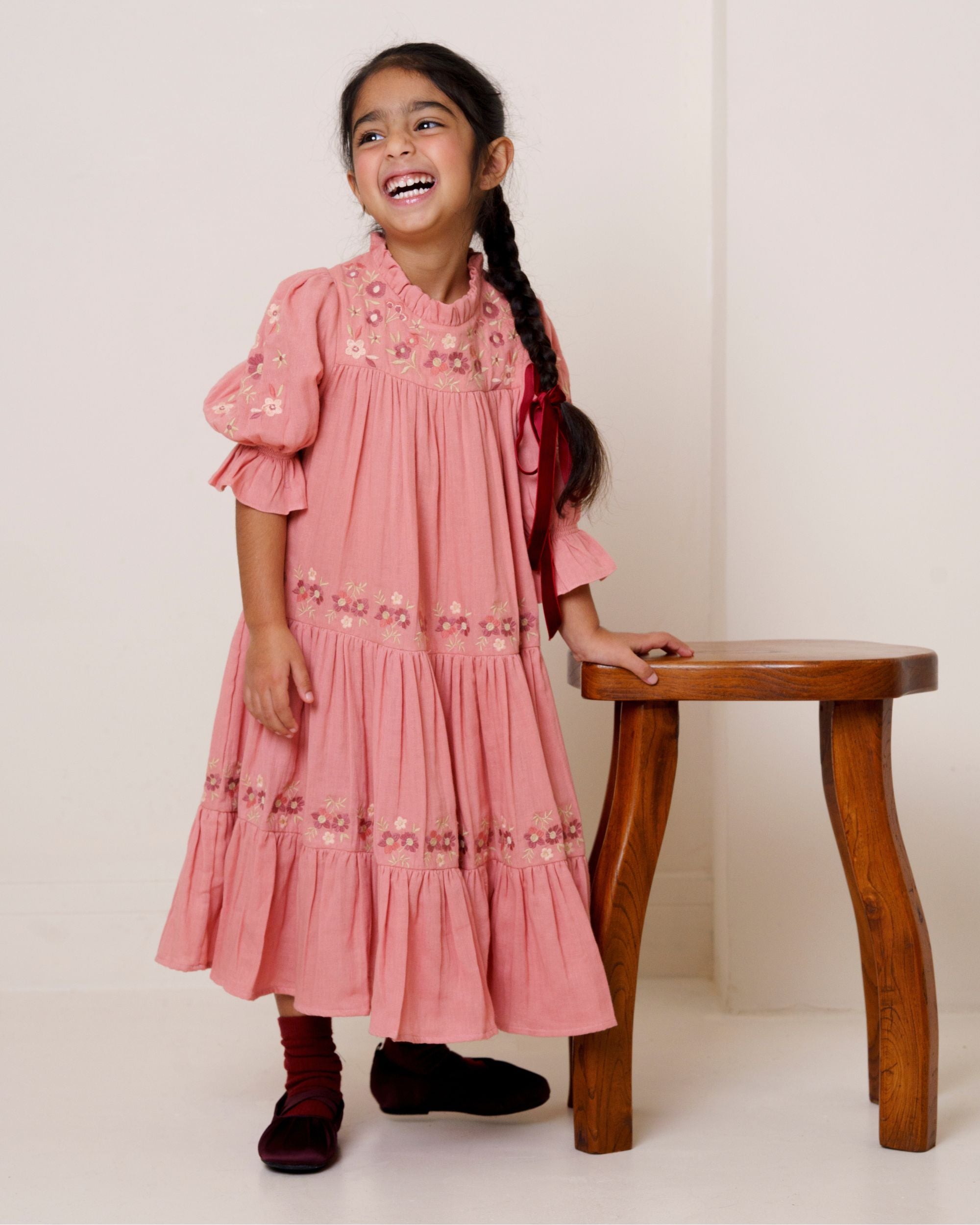 Early Sunday, Lilly Dress in Rose, made from Dyed Cotton Double Gauze fabric, featuring Delicate floral embroidery placed softly across the dress for a timeless, heirloom-inspired finish, shown in a front view of a model wearing it in a studio setting