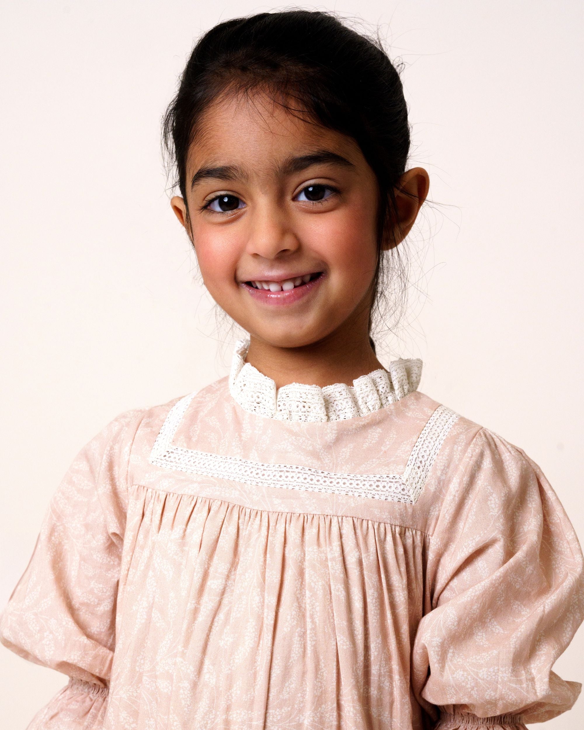 Early Sunday, Lilly Dress in Feather print, made from Printed Cotton Cambric fabric, featuring Delicate floral embroidery placed softly across the dress for a timeless, heirloom-inspired finish, shown in a front view of a model wearing it in a studio setting
