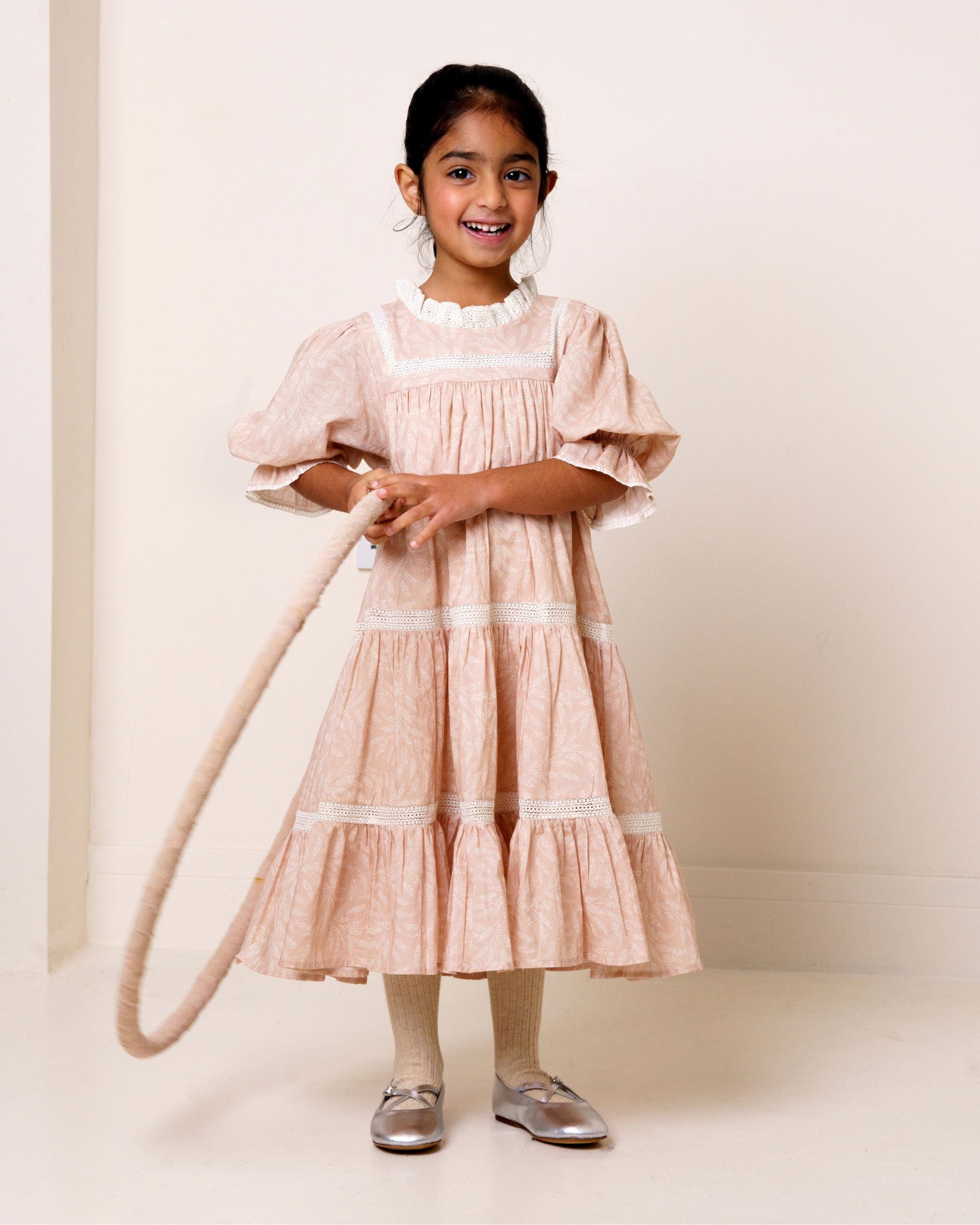 Early Sunday, Lilly Dress in Feather print, made from Printed Cotton Cambric fabric, featuring Delicate floral embroidery placed softly across the dress for a timeless, heirloom-inspired finish, shown in a front view of a model wearing it in a studio setting