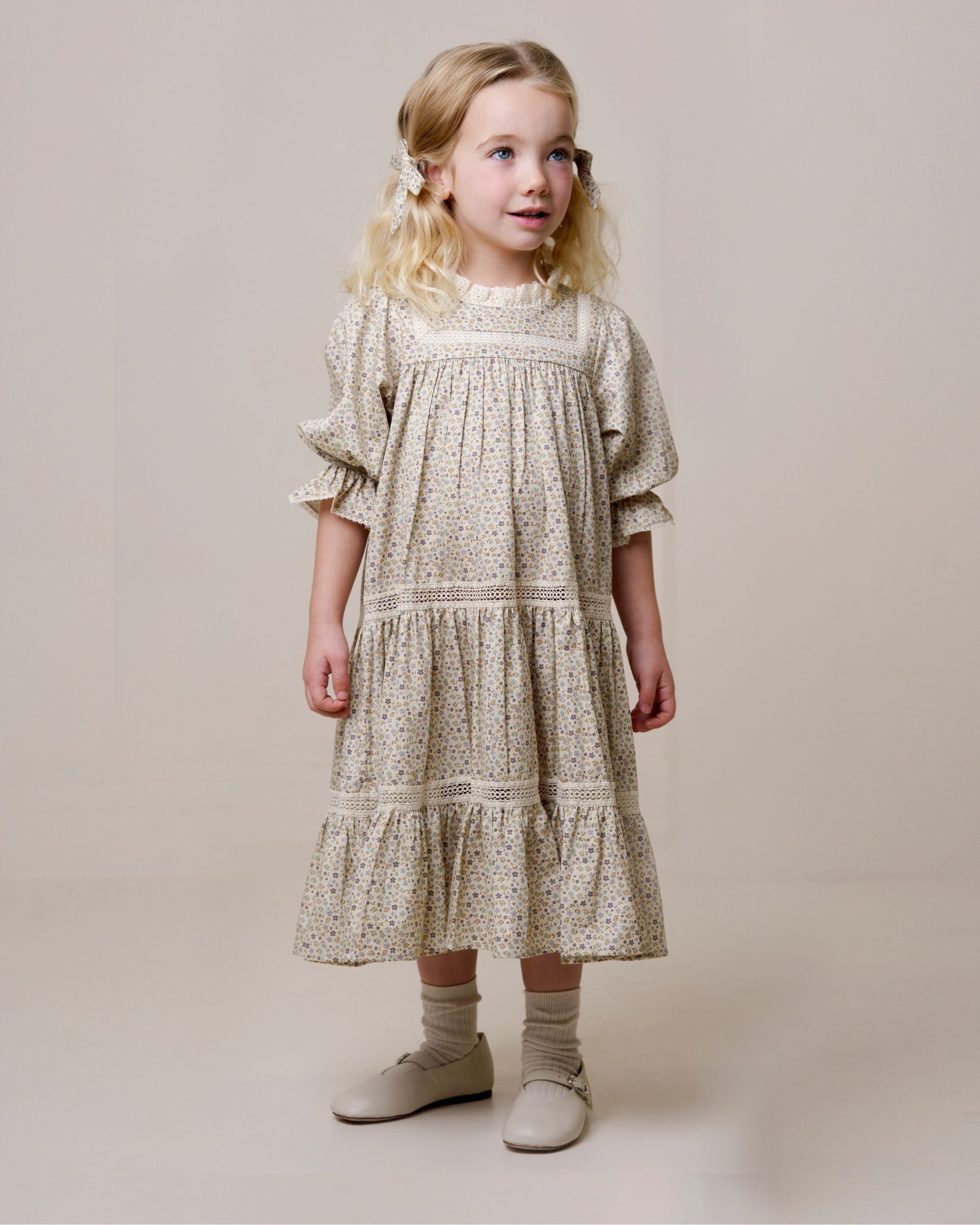 Early Sunday, Lilly Dress in Miny Flowers print, made from Printed Cotton Satin fabric, featuring Delicate floral embroidery placed softly across the dress for a timeless, heirloom-inspired finish, shown in a front view of a model wearing it in a studio setting