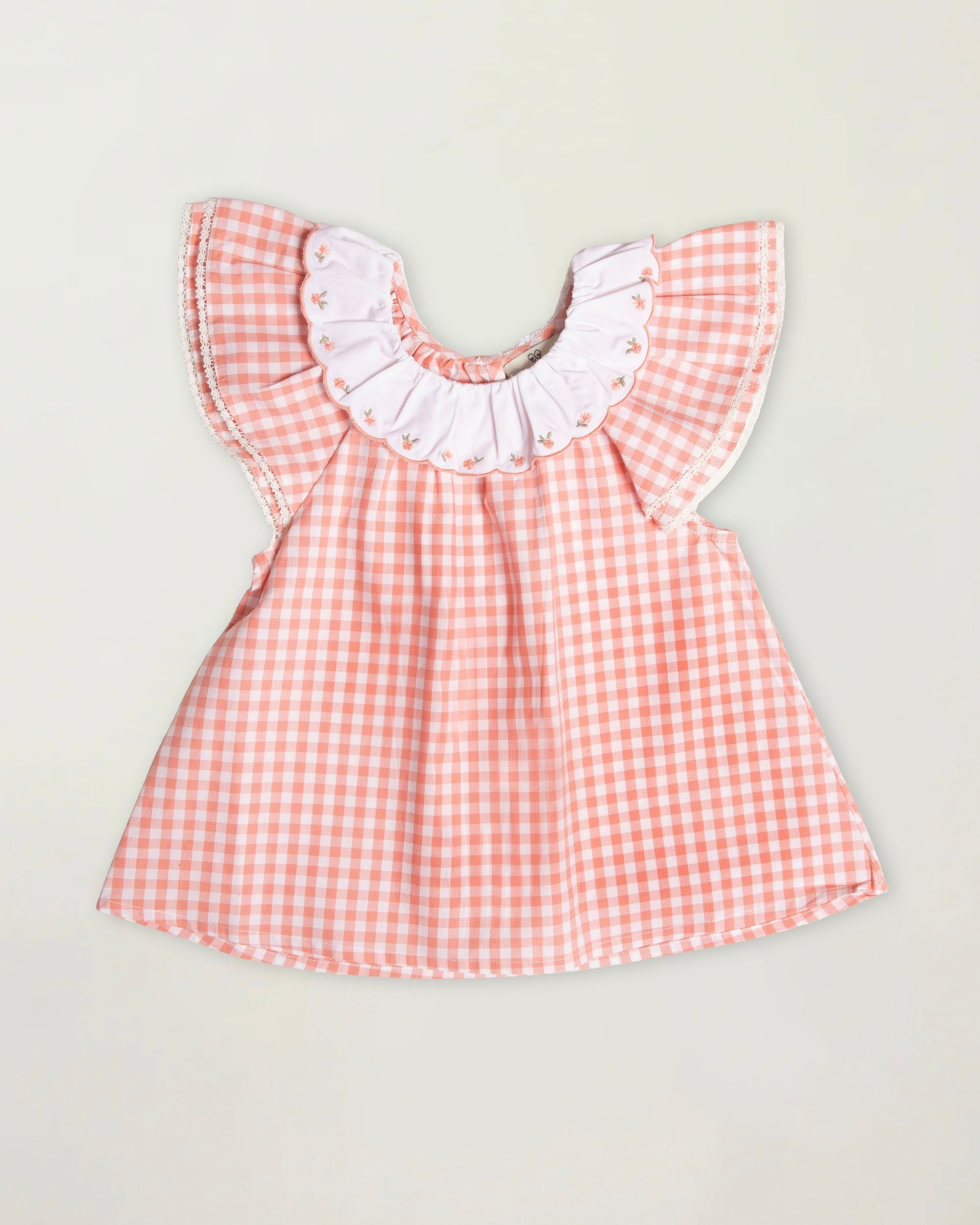 Early Sunday, Lola Blouse in Peony color, made from 100% cotton gingham checks fabric, featuring Ruffled neckline, flutter sleeves with contrast detailing, and gentle gathers for a sweet silhouette, shown in a front flat-lay view
