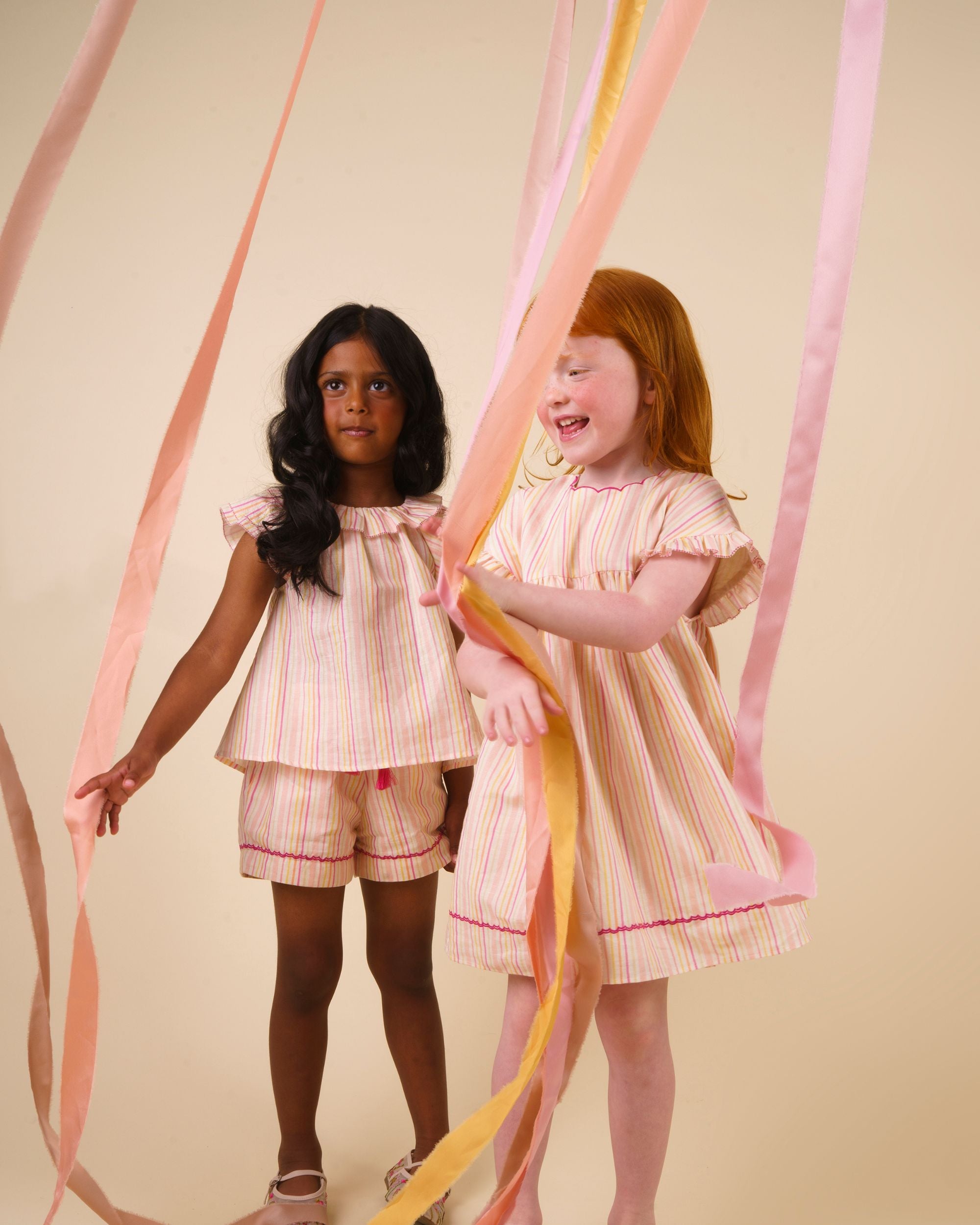 Early Sunday, Lola Blouse in Pink Stripes color, made from printed 70% cotton 30% linen fabric, featuring Ruffled neckline, flutter sleeves with contrast detailing, and gentle gathers for a sweet silhouette, shown in a Model walking / movement shot