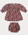 Early Sunday, Lottie Baby Dress & Bloomer Set in Garden Flowers Plum, made from Printed Cotton Satin fabric, featuring a frilly neckline & squared frills around the chest, shown in a front flat-lay view