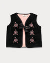 Early Sunday, Lou Vest jacket in Black, made from Cotton Velvet Velour's fabric, featuring sleeveless quilted silhouette with tie-up bow and floral embroidery, shown in a front flat-lay view