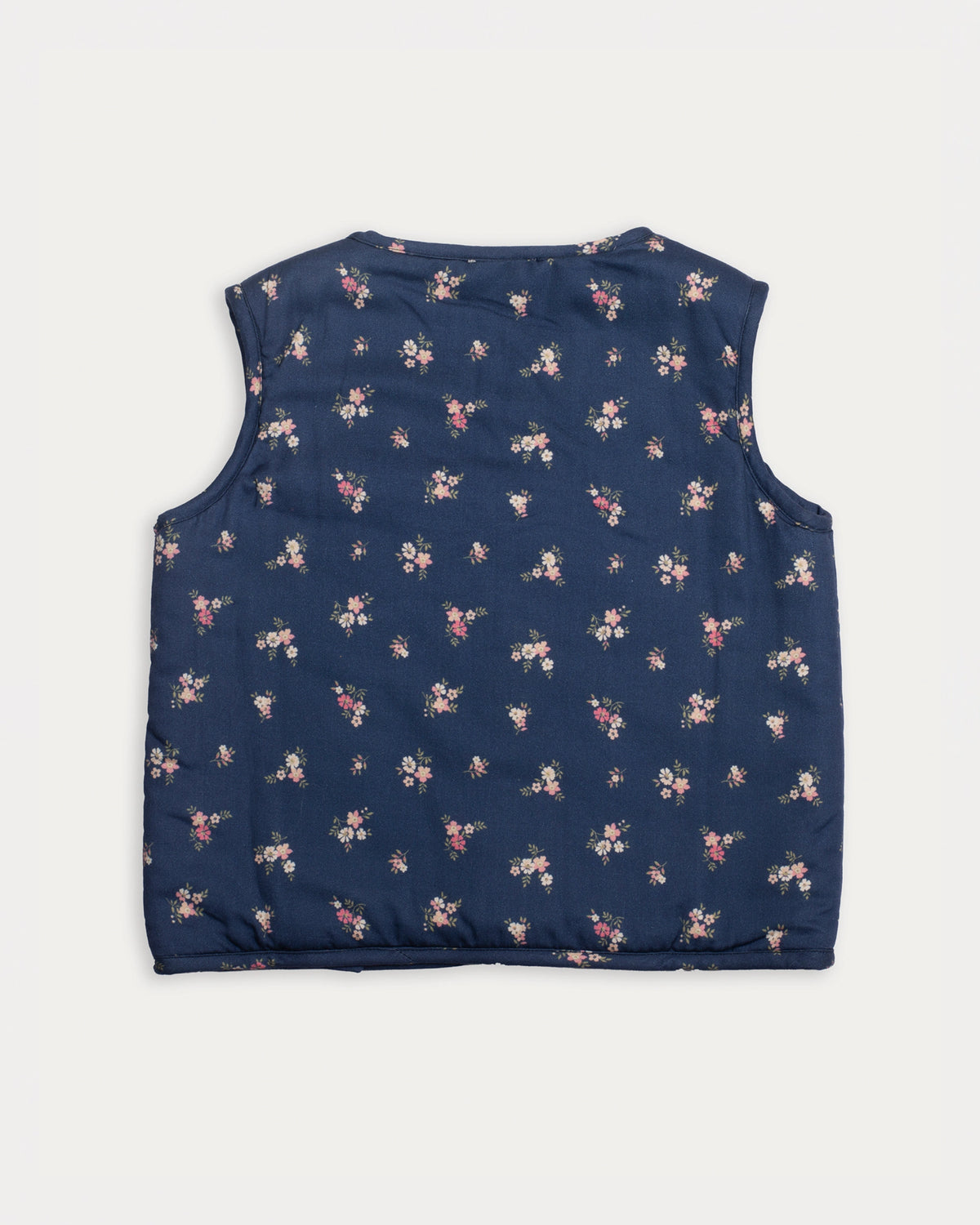 Early Sunday, Lou Vest jacket in Ditsy Bouquet Navy, made from Printed Cotton Satin fabric, featuring sleeveless quilted silhouette with tie-up bow detailing, shown in a back flat-lay view
