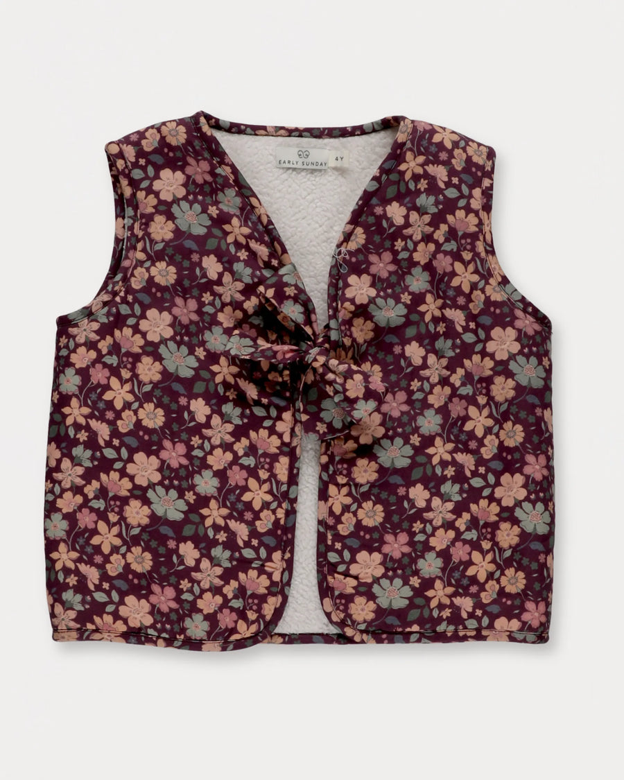 Early Sunday, Lou Vest jacket in Plum, made from Printed Cotton Satin fabric, featuring sleeveless quilted silhouette with tie-up bow detailing, shown in a front flat-lay view